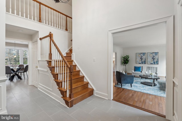 stairs with a towering ceiling, baseboards, and tile patterned floors