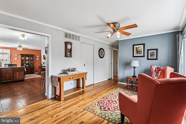 living room featuring crown molding, wood-type flooring, and ceiling fan