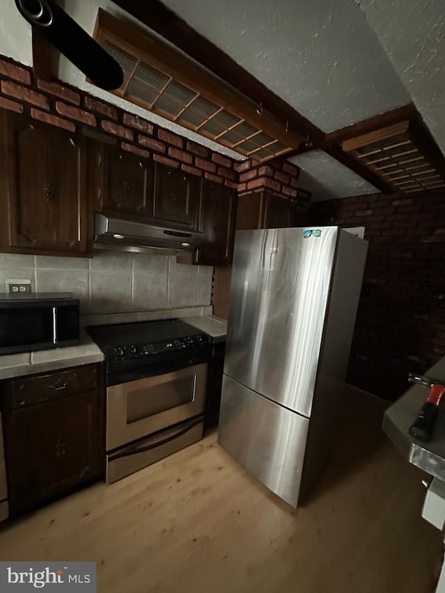 kitchen featuring tasteful backsplash, stainless steel appliances, dark brown cabinets, and light wood-type flooring