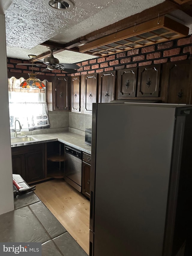 kitchen featuring appliances with stainless steel finishes, sink, ceiling fan, dark brown cabinetry, and light hardwood / wood-style floors