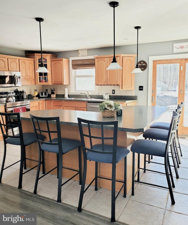 kitchen featuring tasteful backsplash, appliances with stainless steel finishes, light brown cabinetry, and pendant lighting