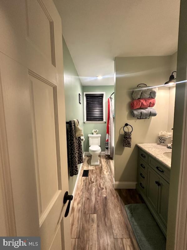 bathroom featuring vanity, hardwood / wood-style flooring, curtained shower, and toilet