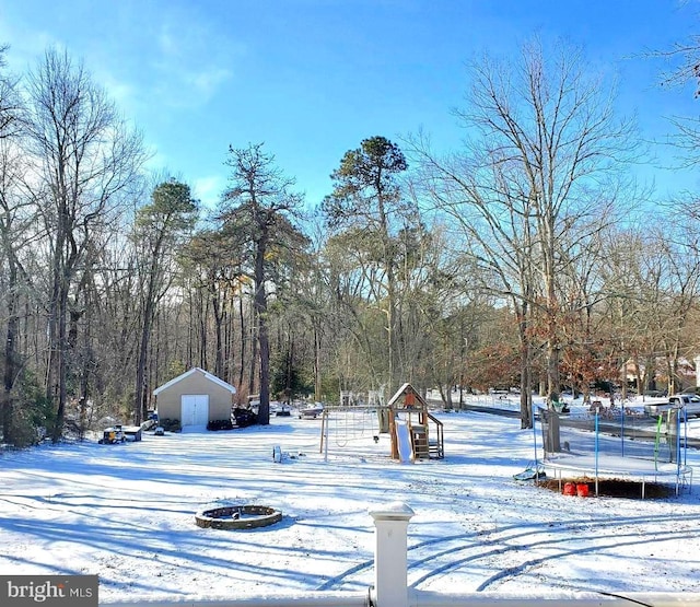 yard covered in snow featuring a playground and a trampoline