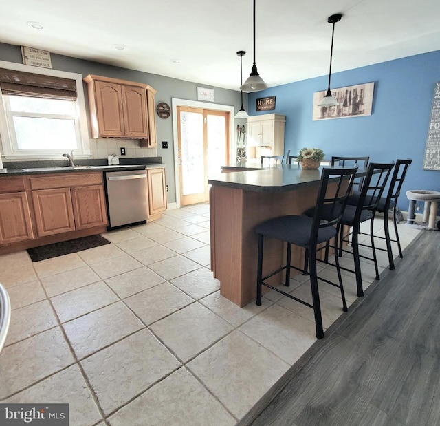 kitchen featuring sink, hanging light fixtures, plenty of natural light, dishwasher, and backsplash