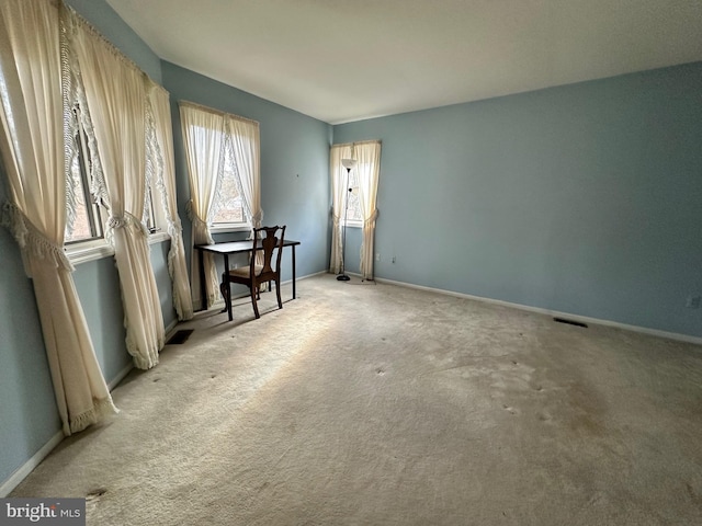 carpeted empty room featuring visible vents and baseboards