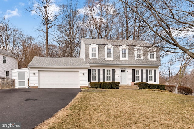 dutch colonial with a shingled roof, fence, a garage, driveway, and a front lawn