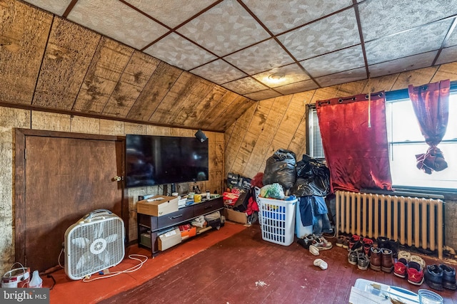 interior space featuring hardwood / wood-style floors, radiator heating unit, wooden walls, and vaulted ceiling