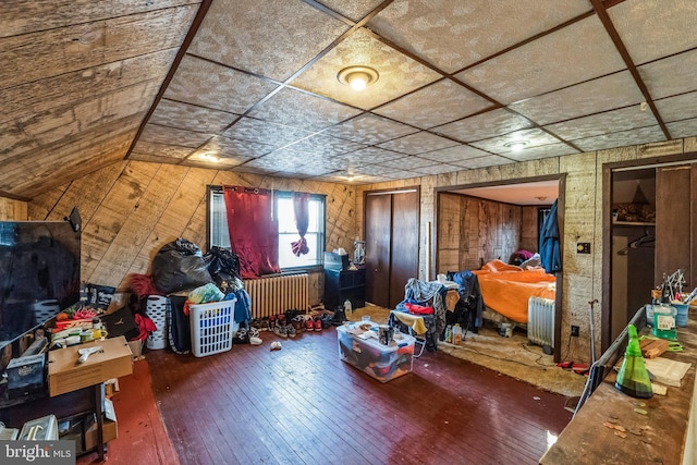 interior space featuring radiator, hardwood / wood-style floors, and wooden walls