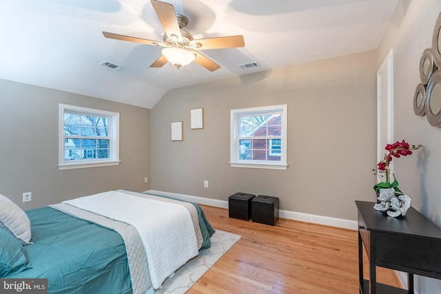 bedroom with light wood-style floors, lofted ceiling, visible vents, and baseboards