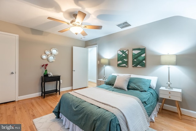 bedroom featuring light wood-style floors, baseboards, visible vents, and ceiling fan