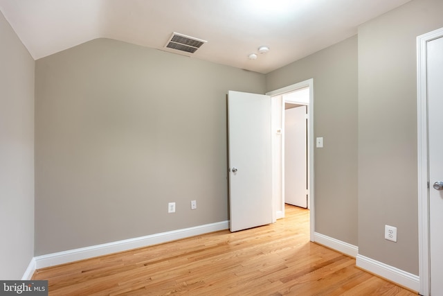 unfurnished bedroom with lofted ceiling, light wood-type flooring, visible vents, and baseboards