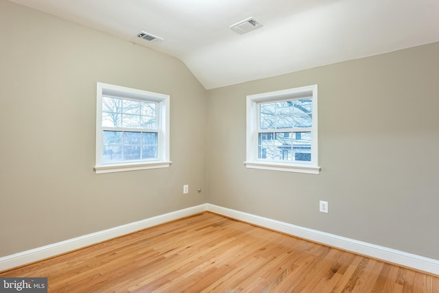 unfurnished room with lofted ceiling, wood finished floors, visible vents, and baseboards