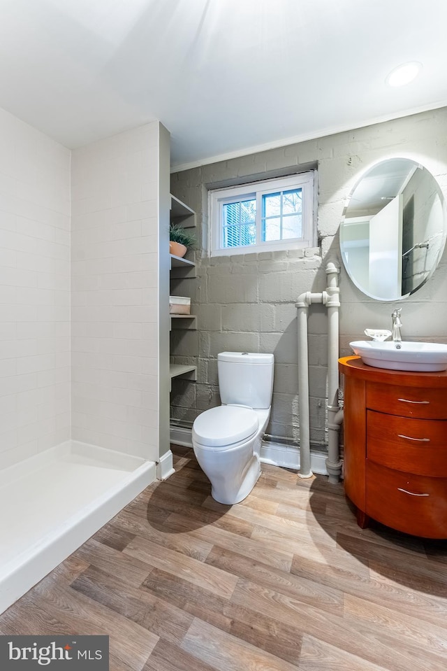 bathroom featuring vanity, tiled shower, wood finished floors, and toilet