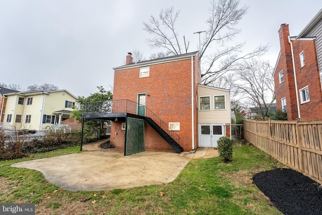 back of house featuring a patio, brick siding, fence, stairs, and a chimney