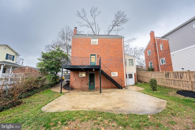 back of property featuring a fenced backyard, stairs, a yard, a patio area, and brick siding