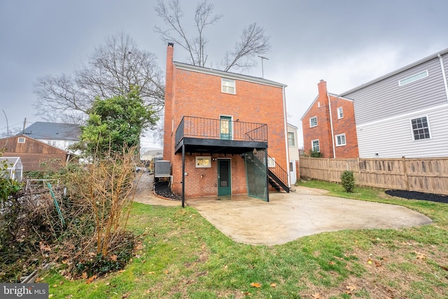 rear view of property with a patio, central AC unit, brick siding, fence, and a yard