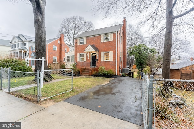 view of front of home featuring a fenced front yard, a chimney, a gate, central AC, and brick siding