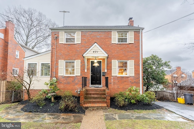 view of front of home with brick siding, fence, and a chimney