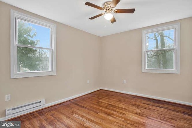 empty room with a healthy amount of sunlight, wood-type flooring, a baseboard heating unit, and ceiling fan