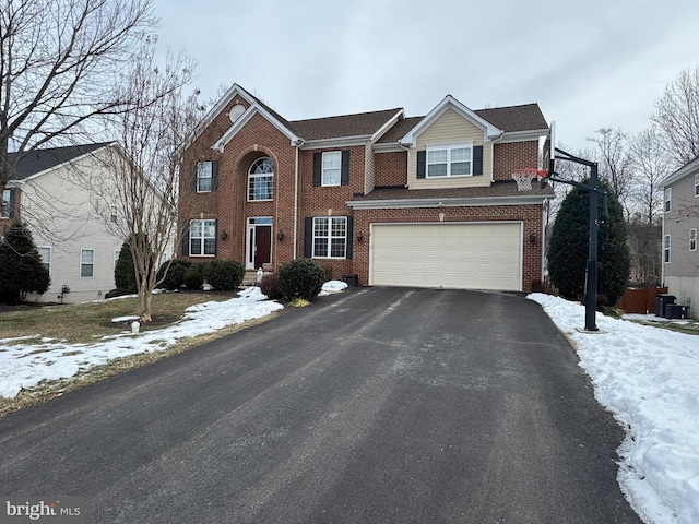 view of front facade featuring aphalt driveway, a garage, and brick siding