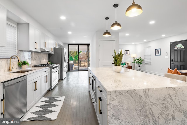 kitchen featuring appliances with stainless steel finishes, pendant lighting, sink, white cabinets, and a center island