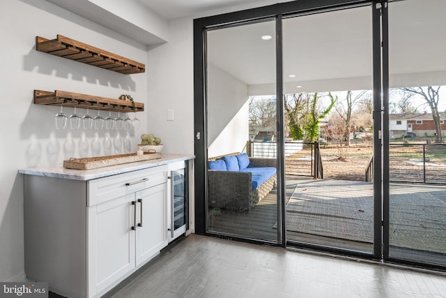 bar featuring beverage cooler, white cabinets, and light wood-type flooring