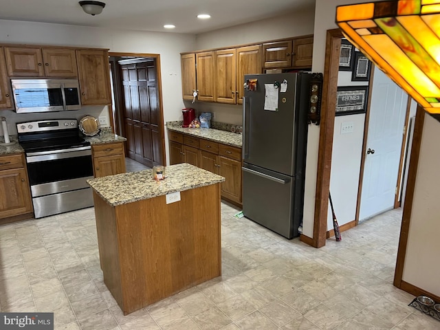 kitchen featuring stainless steel appliances, a kitchen island, and light stone countertops