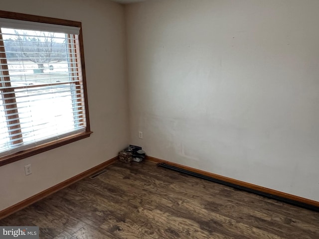 unfurnished room featuring a healthy amount of sunlight and dark hardwood / wood-style flooring