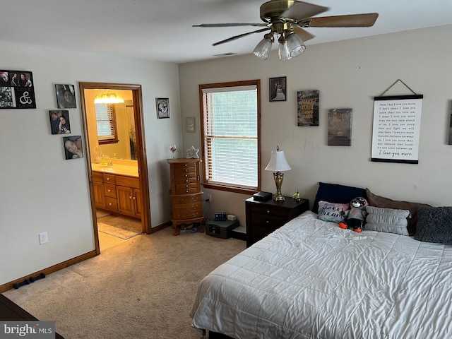 bedroom with ceiling fan, light carpet, and ensuite bath