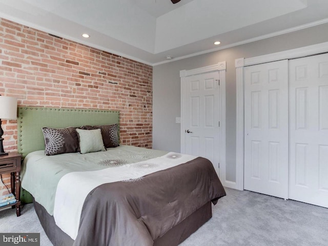 bedroom featuring a closet, brick wall, light carpet, and ornamental molding