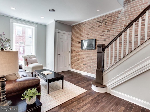 living room featuring ornamental molding, brick wall, and dark hardwood / wood-style floors