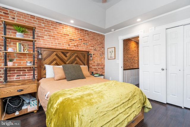 bedroom with crown molding, brick wall, dark hardwood / wood-style floors, and a closet