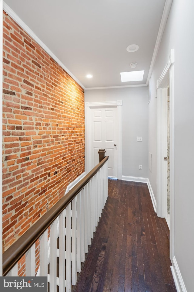 hall featuring crown molding, brick wall, dark hardwood / wood-style floors, and a skylight