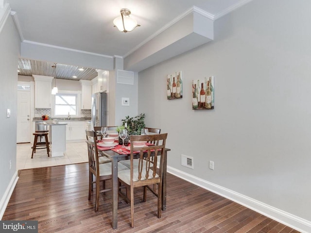 dining area featuring crown molding, sink, and light wood-type flooring