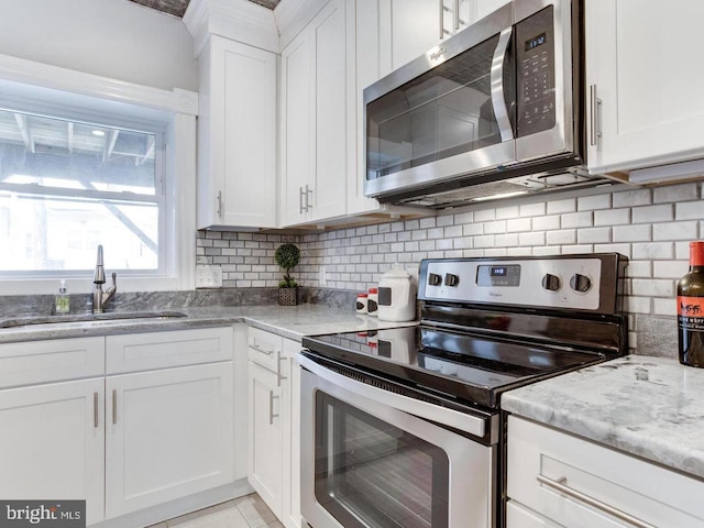 kitchen with white cabinetry, sink, decorative backsplash, stainless steel appliances, and light stone countertops