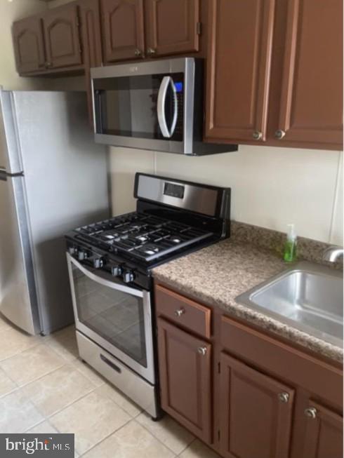 kitchen featuring light tile patterned floors, appliances with stainless steel finishes, and a sink