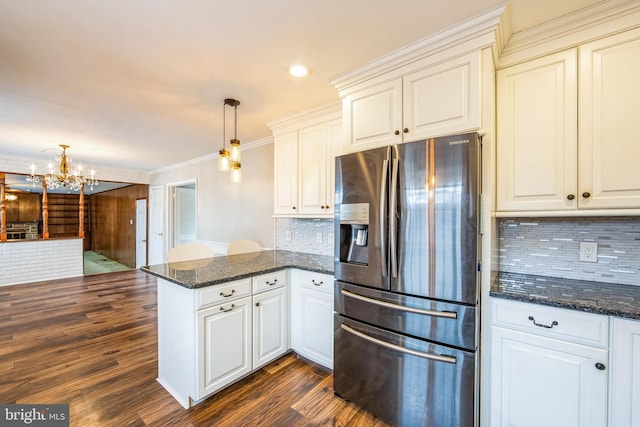 kitchen with hanging light fixtures, stainless steel refrigerator with ice dispenser, dark hardwood / wood-style flooring, kitchen peninsula, and dark stone counters