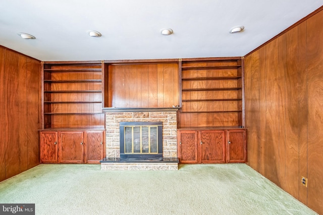 unfurnished living room featuring light carpet, a fireplace, and wood walls