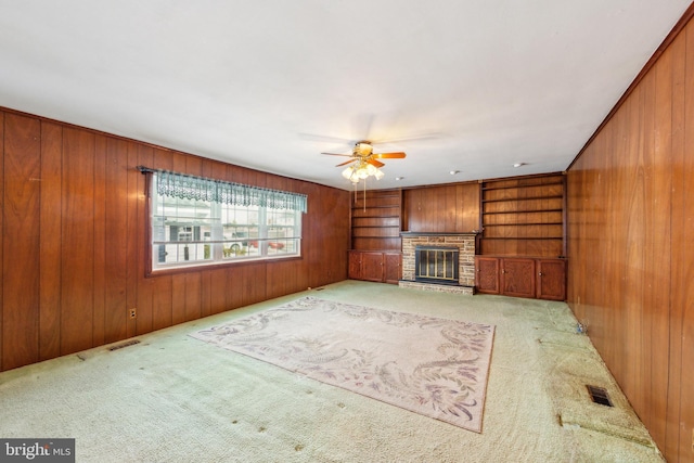 unfurnished living room with light carpet, a brick fireplace, and wood walls