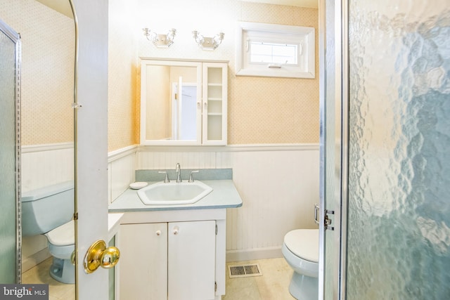 bathroom with tile patterned flooring, vanity, a shower with shower door, and toilet