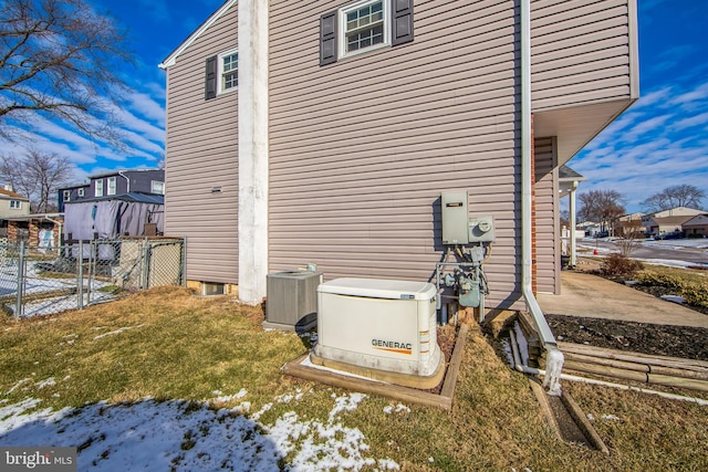 view of snowy exterior featuring a yard and central AC unit