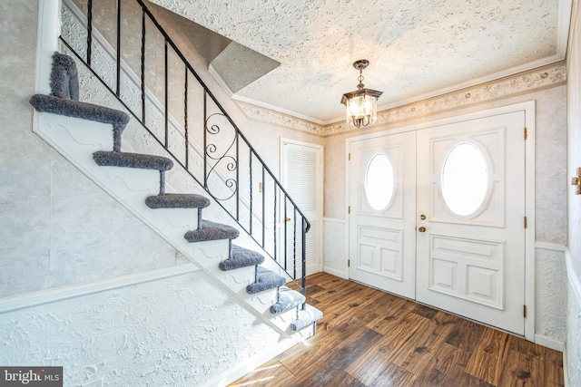 entryway featuring an inviting chandelier, dark wood-type flooring, and ornamental molding