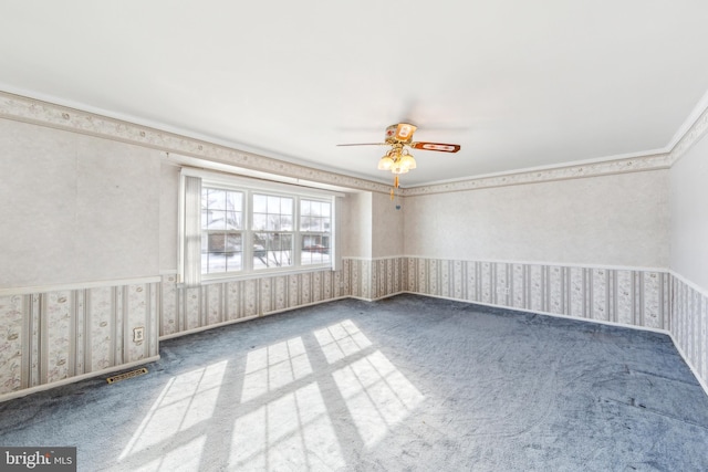 empty room with crown molding, ceiling fan, and carpet