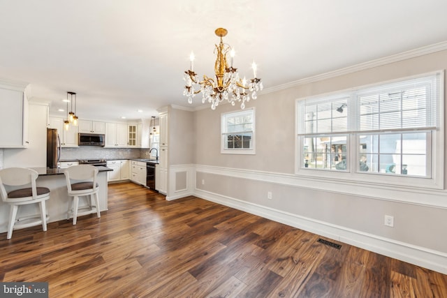 kitchen featuring sink, stainless steel appliances, dark hardwood / wood-style floors, white cabinets, and decorative light fixtures