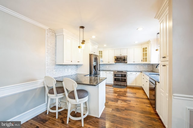 kitchen featuring pendant lighting, a breakfast bar area, white cabinetry, stainless steel appliances, and kitchen peninsula