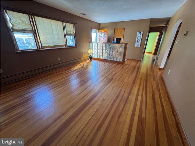 spare room featuring baseboard heating and hardwood / wood-style floors