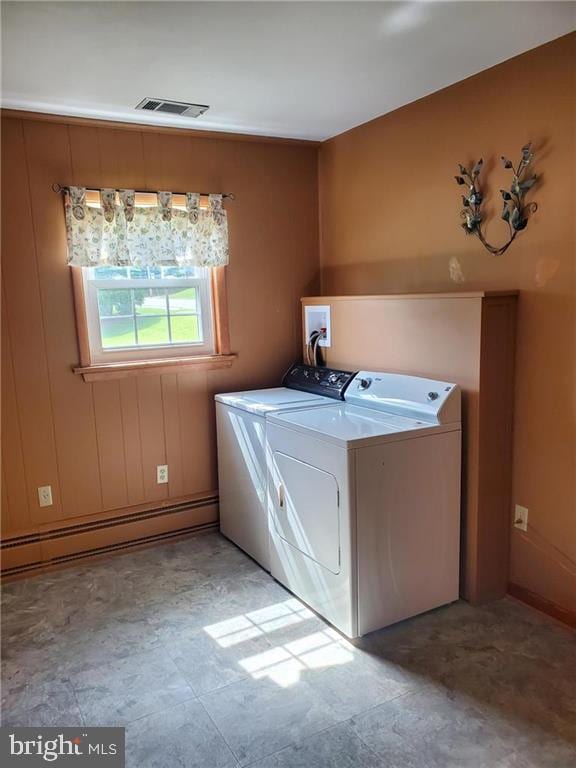 clothes washing area featuring a baseboard radiator and washer and dryer