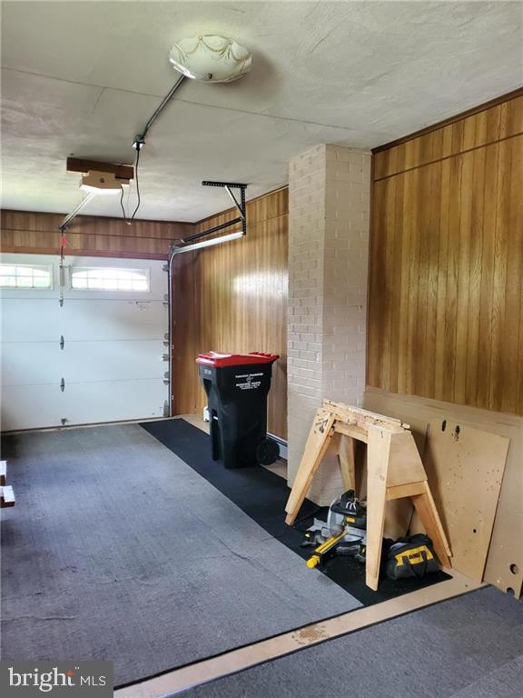 garage with a garage door opener and wooden walls