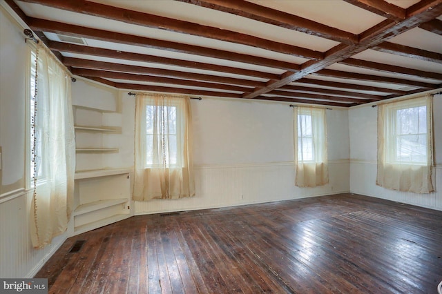 empty room featuring beamed ceiling and dark hardwood / wood-style flooring