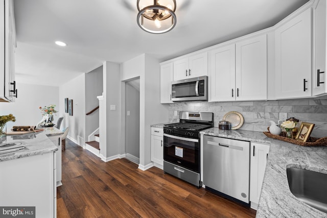 kitchen with stainless steel appliances, light stone countertops, and white cabinets